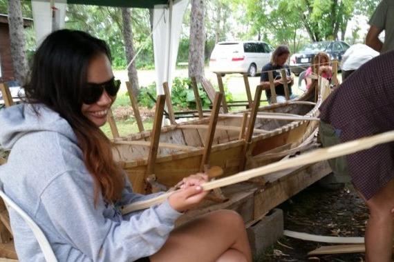 一个女学生拿着一块木头站在一个大木船旁边